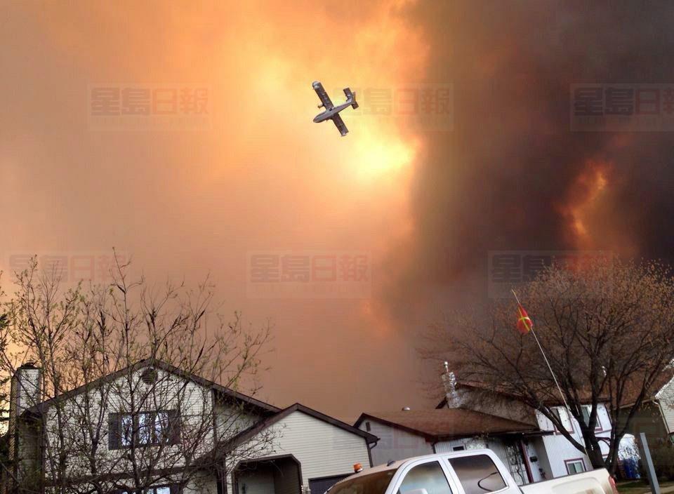 Smoke fills the air as a small plane flies overhead in Fort McMurray, Alberta on Tuesday May 3, 2016. Raging forest fires whipped up by shifting winds sliced through the middle of the remote oilsands hub city of Fort McMurray Tuesday, sending tens of thousands fleeing in both directions and prompting the evacuation of the entire city. THE CANADIAN PRESS/Kitty Cochrane