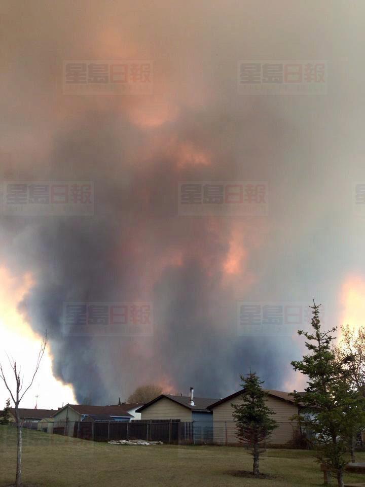 Fire burns and smoke fills the air near homes in Fort McMurray, Alberta on Tuesday May 3, 2016. Raging forest fires whipped up by shifting winds sliced through the middle of the remote oilsands hub city of Fort McMurray Tuesday, sending tens of thousands fleeing in both directions and prompting the evacuation of the entire city. THE CANADIAN PRESS/Kitty Cochrane