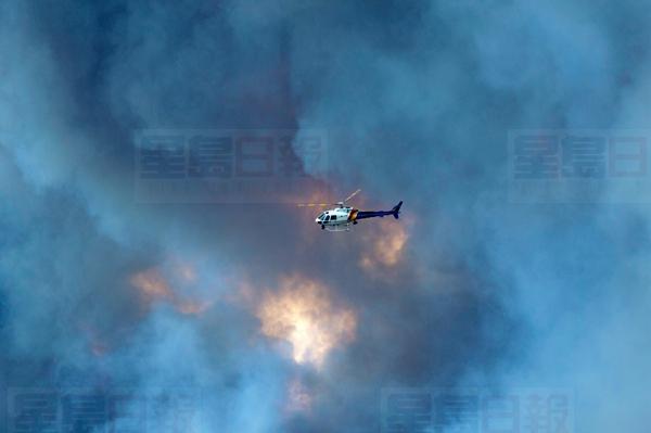 A RCMP helicopter flies past a wild fire 30km south of Fort McMurray, Alberta on highway 63 Friday, May 6, 2016. Officials said shifting winds were giving the embattled northern Alberta city a break, but they added the fire that forced 80,000 people from their homes remained out of control and was likely to burn for weeks.THE CANADIAN PRESS/Jonathan Hayward