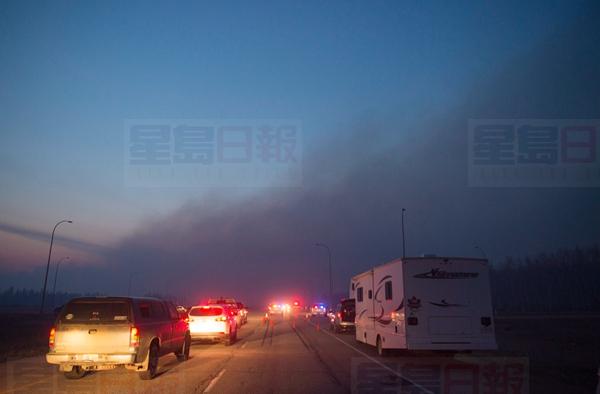 RCMP cars and officers man a checkpoint on the highway to Fort McMurray, Alberta as wildfires are still burning out of control Friday, May 6, 2016.THE CANADIAN PRESS/Ryan Remiorz
