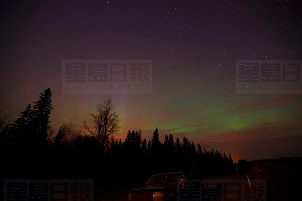 The northern lights shine above the glow from a wildfire on highway 63 south of Fort McMurray, Alta., on Friday, May 6, 2016. THE CANADIAN PRESS/Jonathan Hayward