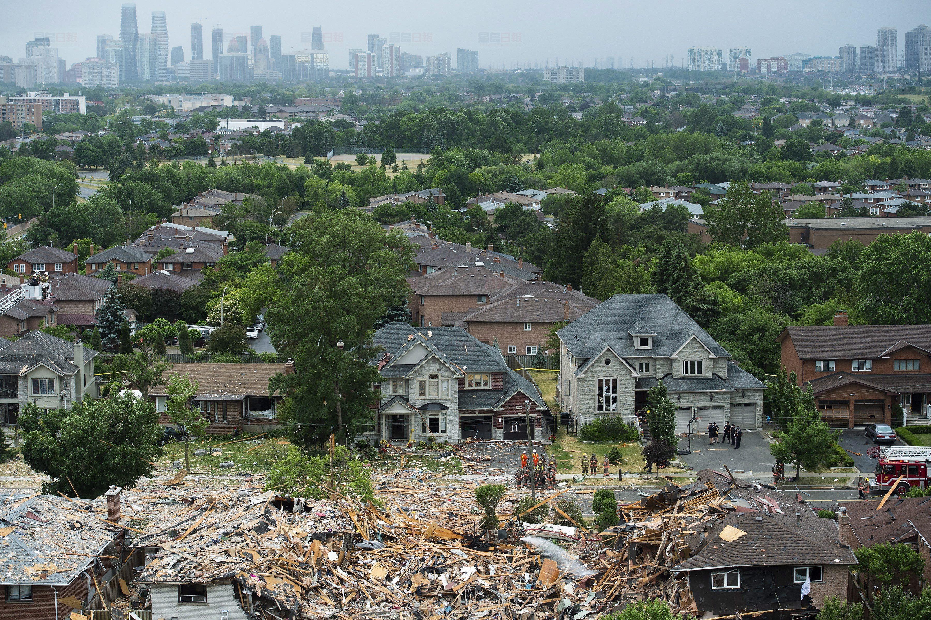 Firefighters and emergency personal work at the scene after a home explosion happened in Mississauga, Ont., on Tuesday, June 28, 2016. THE CANADIAN PRESS/Nathan Denette