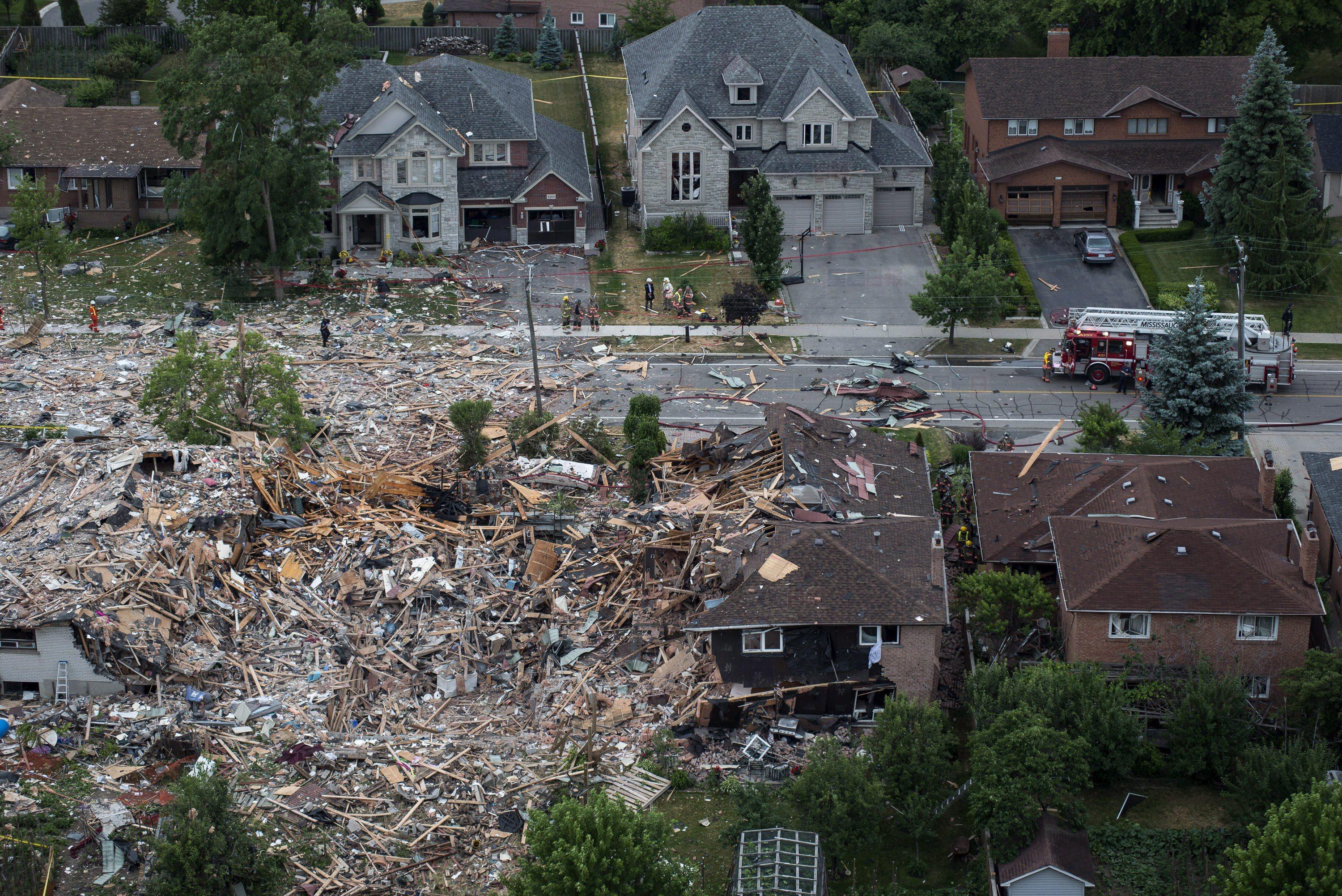 Firefighters examine debris after a house explosion in Mississauga, Ont., Tuesday, June 28, 2016. THE CANADIAN PRESS/Eduardo Lima.