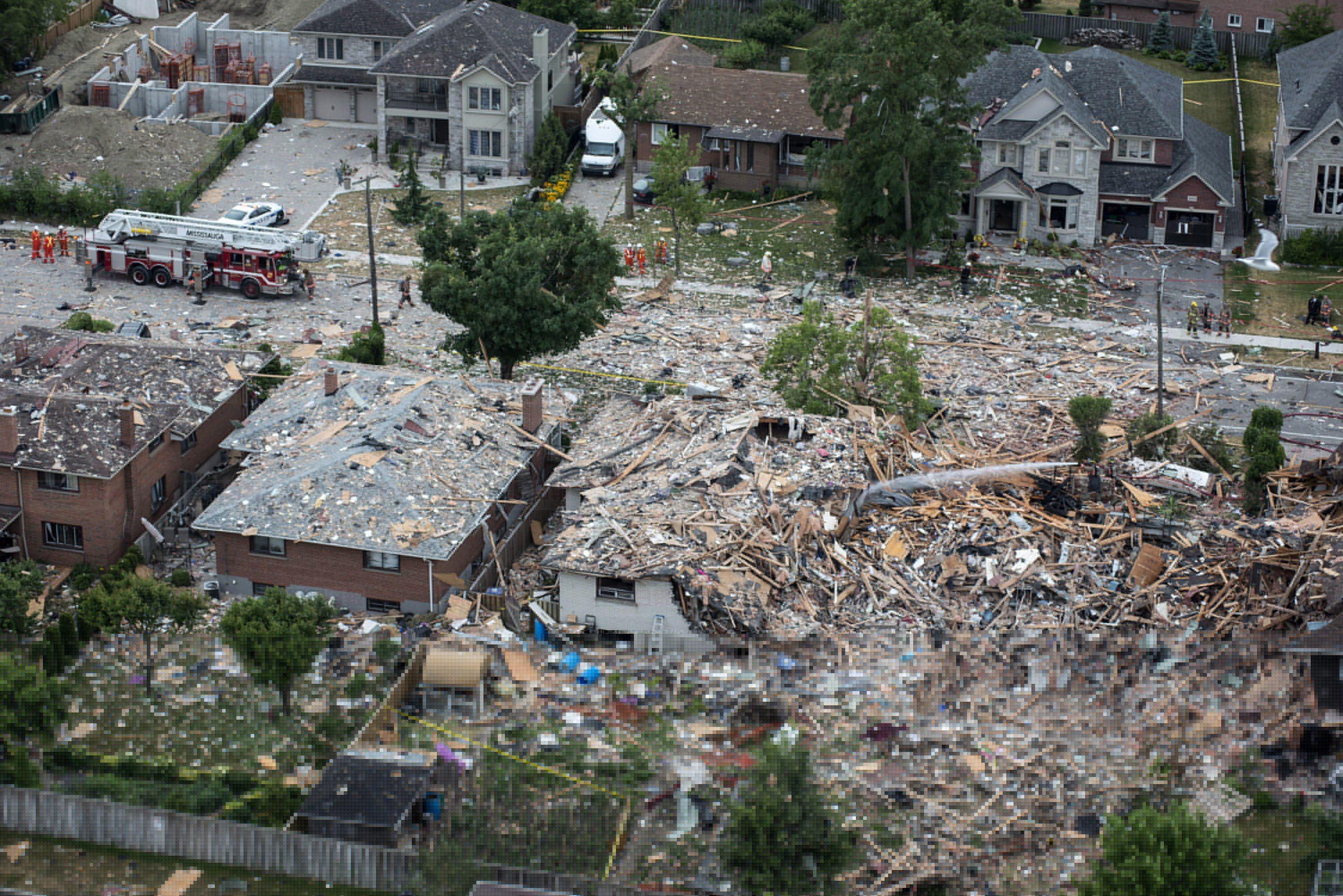 Firefighters examine debris after a house explosion in Mississauga, Ont., Tuesday, June 28, 2016. THE CANADIAN PRESS/Eduardo Lima.
