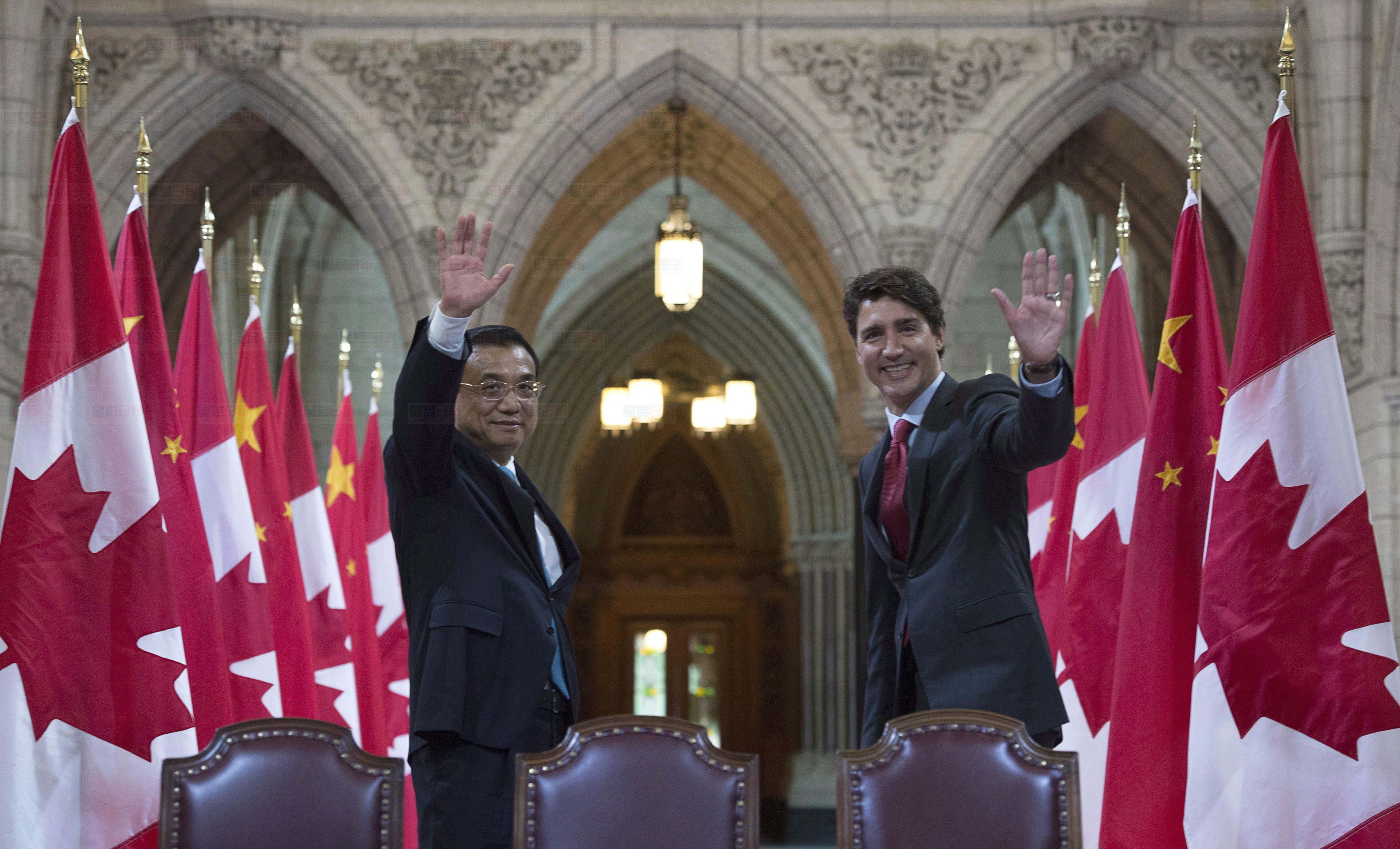 Canadian Prime Minister Justin Trudeau and Chinese Premier Li Keqiang wave to photographers following a signing ceremony in the Hall of Honour on Parliament Hill in Ottawa, Thursday September 22, 2016. THE CANADIAN PRESS/Adrian Wyld