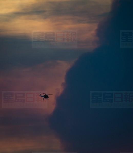 A firefighting helicopter flies past smoke in the air from a wildfire burning near Ashcroft, B.C., at sunset on Friday July 7, 2017. THE CANADIAN PRESS/Darryl Dyck