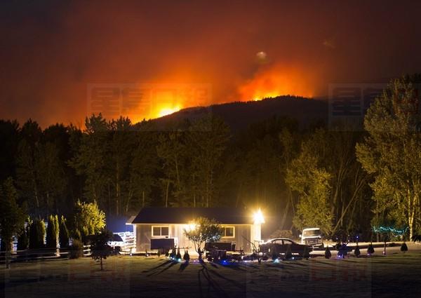 A wildfire burns on a mountain behind a home in Cache Creek, B.C., in the early morning hours of Saturday July 8, 2017. More than 3,000 residents have been evacuated from their homes in central British Columbia. A provincial state of emergency was declared after 56 new wildfires started Friday. THE CANADIAN PRESS/Darryl Dyck