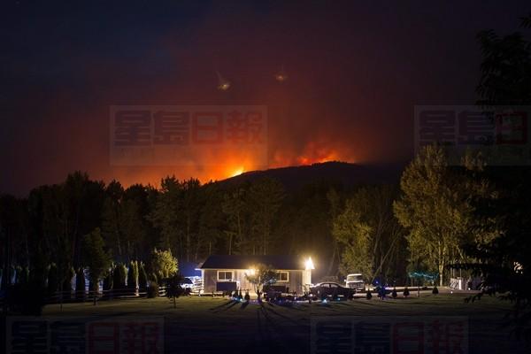 A wildfire burns on a mountain behind a home in Cache Creek, B.C., in the early morning hours of Saturday July 8, 2017. More than 3,000 residents have been evacuated from their homes in central British Columbia. A provincial state of emergency was declared after 56 new wildfires started Friday. THE CANADIAN PRESS/Darryl Dyck