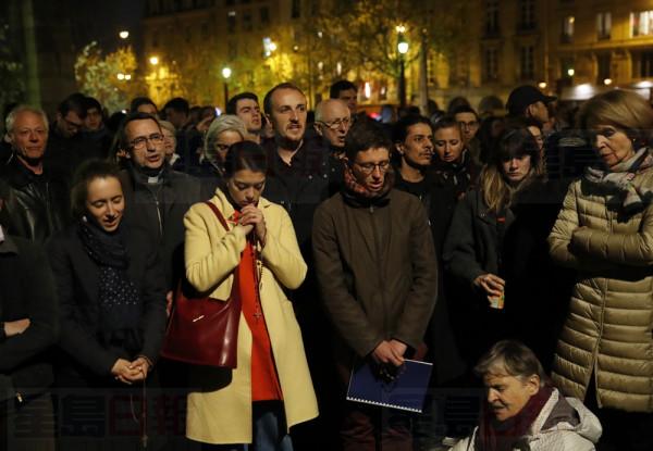 People pray as Notre Dame cathedral is burning in Paris, Monday, April 15, 2019. A catastrophic fire engulfed the upper reaches of Paris' soaring Notre Dame Cathedral as it was undergoing renovations Monday, threatening one of the greatest architectural treasures of the Western world as tourists and Parisians looked on aghast from the streets below. (AP Photo/Christophe Ena)