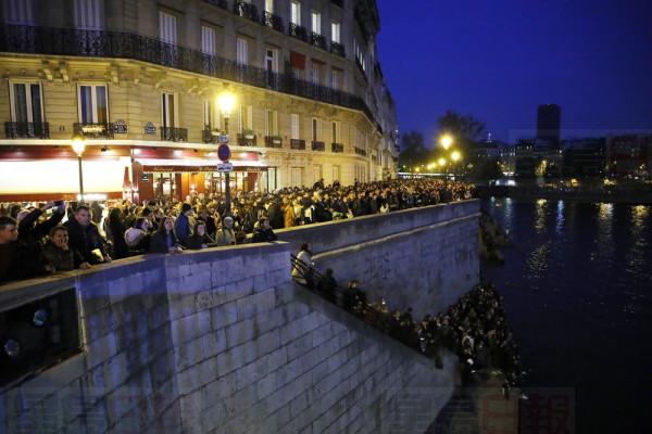 People watch Notre Dame cathedral burning from the Seine river banks in Paris, Monday, April 15, 2019. A catastrophic fire engulfed the upper reaches of Paris' soaring Notre Dame Cathedral as it was undergoing renovations Monday, threatening one of the greatest architectural treasures of the Western world as tourists and Parisians looked on aghast from the streets below. (AP Photo/Francois Mori)