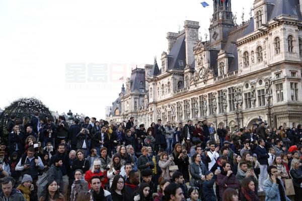People watch as flames and smoke rise from Notre Dame cathedral as it burns in Paris, Monday, April 15, 2019. Massive plumes of yellow brown smoke is filling the air above Notre Dame Cathedral and ash is falling on tourists and others around the island that marks the center of Paris. (AP Photo/Thibault Camus)