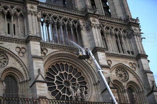 A fire fighter sprays a liquid into Notre Dame cathedral while the monument is burning in Paris, Monday, April 15, 2019. A catastrophic fire engulfed the upper reaches of Paris' soaring Notre Dame Cathedral as it was undergoing renovations Monday, threatening one of the greatest architectural treasures of the Western world as tourists and Parisians looked on aghast from the streets below. (AP Photo/Francois Mori)