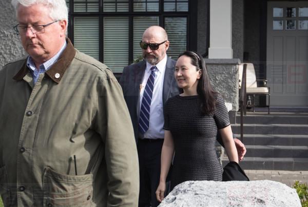 Huawei chief financial officer Meng Wanzhou, back right, who is out on bail and remains under partial house arrest after she was detained Dec. 1 at the behest of American authorities, is accompanied by a private security detail as she leaves her home to attend a court appearance in Vancouver, on Wednesday May 8, 2019. THE CANADIAN PRESS/Darryl Dyck