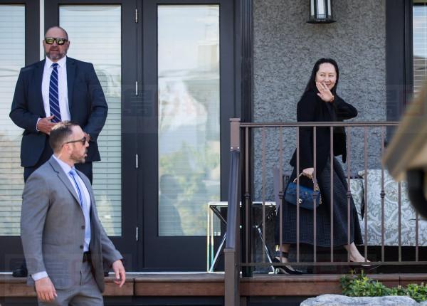 Huawei chief financial officer Meng Wanzhou, right, who is out on bail and remains under partial house arrest after she was detained Dec. 1 at the behest of American authorities, waves as she returns home after attending a court appearance in Vancouver, on Wednesday May 8, 2019. THE CANADIAN PRESS/Darryl Dyck