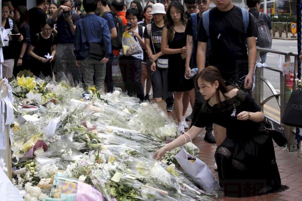 Mourners stop by a makeshift memorial, to lay flowers and pray for a man who fell to his death Saturday after hanging a protest banner against an extradition bill in Hong Kong Sunday, June 16, 2019. Tens of thousands of Hong Kong residents, mostly in black, have jammed the citys streets Sunday to protest the governments handling of a proposed extradition bill. (AP Photo/Kin Cheung)