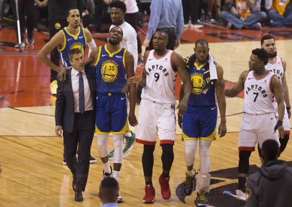 Golden State Warriors forward Kevin Durant (35) walks off the court after sustaining an injury as he's consoled by Toronto Raptors centre Serge Ibaka (9) as Warriors forward Andre Iguodala (9) and Raptors guard Kyle Lowry (7) look on during first half basketball action in Game 5 of the NBA Finals in Toronto on Monday, June 10, 2019. THE CANADIAN PRESS/Chris Young