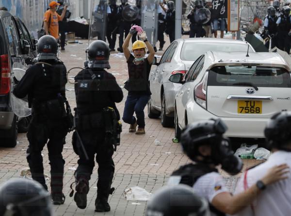 A protester raises his hands after riot police fire tear gas to protesters outside the Legislative Council in Hong Kong, Wednesday, June 12, 2019. Hong Kong police have used tear gas and high-pressure hoses against thousands of protesters opposing a highly controversial extradition bill outside government headquarters. (AP Photo/Vincent Yu)