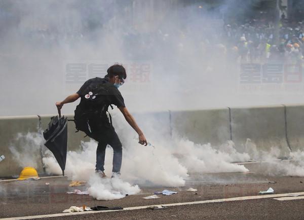A protester using water to extinguish tear gas fired by police during a huge demonstration outside the Legislative Council in Hong Kong, Wednesday, June 12, 2019. Hong Kong police have used tear gas and high-pressure hoses against thousands of protesters opposing a highly controversial extradition bill outside government headquarters. (AP Photo/Kin Cheung)
