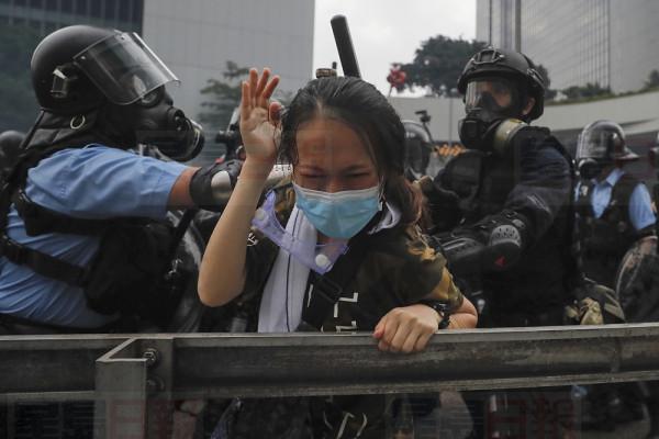A protester reacts as she tackled by riot police during a massive demonstration outside the Legislative Council in Hong Kong, Wednesday, June 12, 2019. Hong Kong police have used tear gas and high-pressure hoses against thousands of protesters opposing a highly controversial extradition bill outside government headquarters. (AP Photo/Kin Cheung)