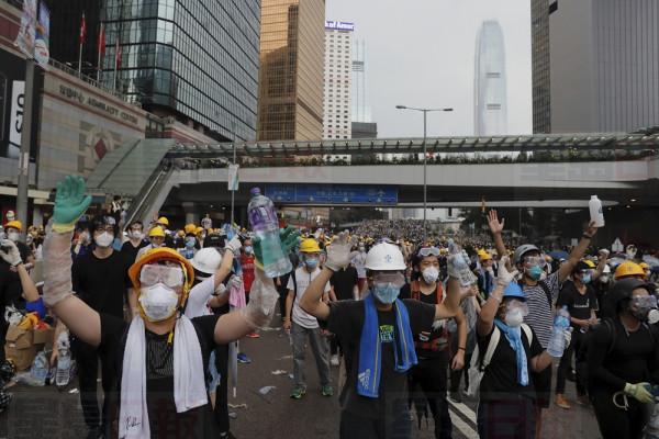Protesters gesture to riot police during a massive demonstration outside the Legislative Council in Hong Kong, Wednesday, June 12, 2019. Hong Kong police have used tear gas and high-pressure hoses against thousands of protesters opposing a highly controversial extradition bill outside government headquarters. (AP Photo/Kin Cheung)