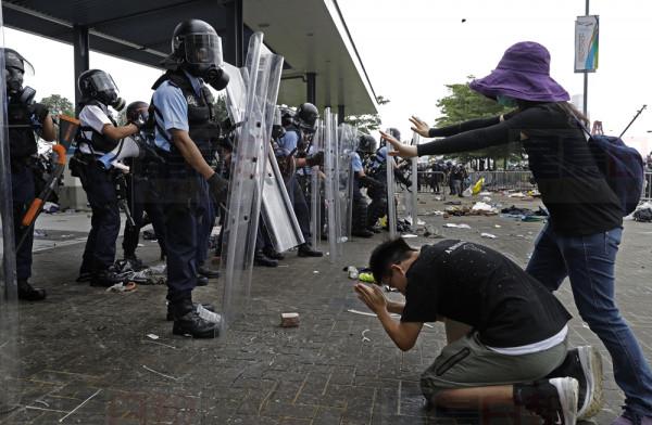 A protester bows to riot police after they fire tear gas towards protesters outside the Legislative Council in Hong Kong, Wednesday, June 12, 2019. Hong Kong police used tear gas and high-pressure water hoses against protesters who had massed outside government headquarters Wednesday in opposition to a proposed extradition bill that has become a lightning rod for concerns over greater Chinese control and erosion of civil liberties in the semiautonomous territory. (AP Photo/Vincent Yu)