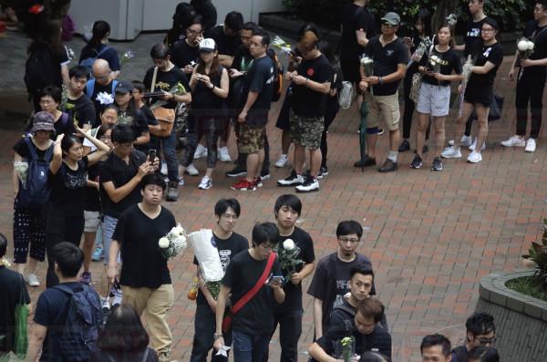 Mourners queue to stop by a makeshift memorial, to lay flowers and pray for a man who fell to his death Saturday after hanging a protest banner against an extradition bill in Hong Kong on Sunday, June 16, 2019. Tens of thousands of Hong Kong residents, mostly in black, have jammed the citys streets Sunday to protest the governments handling of a proposed extradition bill. (AP Photo/Kin Cheung)