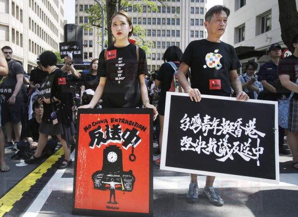 Supporters march with slogans reading "No Extradition to China" and "Taiwan Youth Support Hong Kong. No Extradition to China firmly" to oppose a Hong Kong extradition law outside of Legislative Yuan in Taipei, Taiwan, Sunday, June 16, 2019. Hong Kong residents Sunday continued their massive protest over an unpopular extradition bill that has highlighted the territory's apprehension about relations with mainland China, a week after the crisis brought as many as 1 million into the streets. (AP Photo/Chiang Ying-ying)