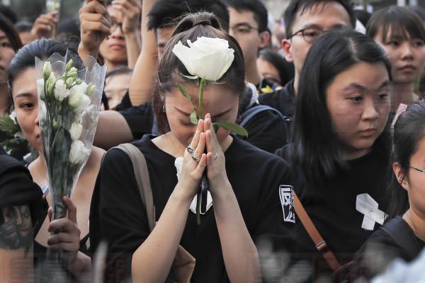 Mourners hold flowers pray for a man who fell to his death on Saturday after hanging a protest banner against an extradition bill in Hong Kong Sunday, June 16, 2019. Hong Kong residents were gathering Sunday for another massive protest over an unpopular extradition bill that has highlighted the territory's apprehension about relations with mainland China. (AP Photo/Kin Cheung)