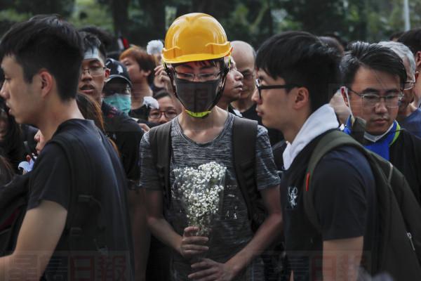 Mourners hold flowers pray for a man who fell to his death on Saturday after hanging a protest banner against an extradition bill in Hong Kong Sunday, June 16, 2019. Hong Kong residents were gathering Sunday for another mass protest over an unpopular extradition bill that has highlighted the territory's apprehension about relations with mainland China. (AP Photo/Kin Cheung)