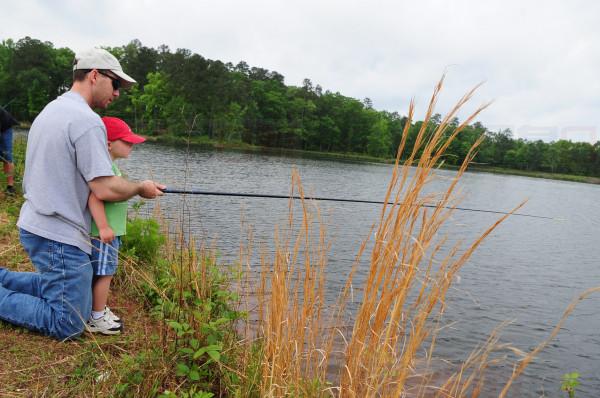 Maj. Kenn Cates teaches his son Parker, 3, how to fish during the kid fish event held April 25. Major Cates was one of many parents who spent the day teaching their child to fish for the first time. (U.S. Air Force photo by Senior Airman Joanna M. Kresge)