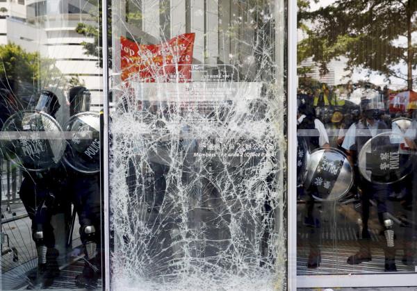 Police officers stand guard behind the cracked glass wall of the Legislative Council after protesters try to break into in Hong Kong on Monday, July 1, 2019. Combative protesters tried to break into the Hong Kong legislature Monday as a crowd of thousands prepared to start a march in that direction on the 22nd anniversary of the former British colony's return to China. (AP Photo/Vincent Yu)