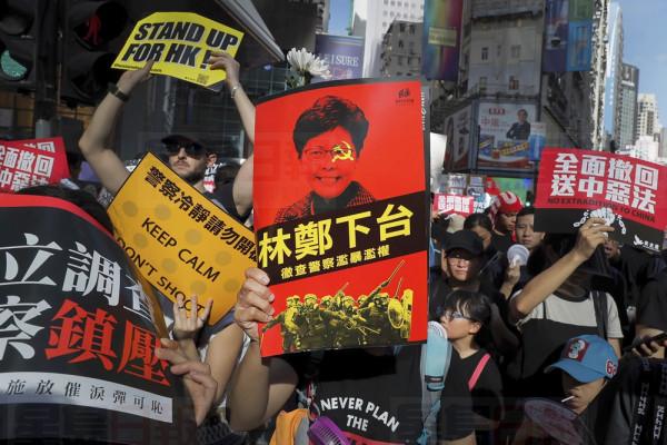 Protesters hold placards march in a rally in Hong Kong, Monday, July 1, 2019. Combative protesters tried to break into the Hong Kong legislature Monday as a crowd of thousands prepared to start a march in that direction on the 22nd anniversary of the former British colony's return to China. A placard reads "Carrie Lam step down". (AP Photo/Kin Cheung)