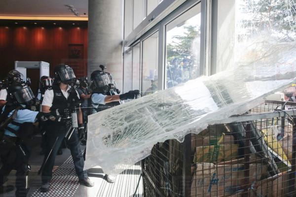 Police officers spray pepper spray as protesters use a cart to ram into the glass wall of the Legislative Council in Hong Kong on Monday, July 1, 2019. The embattled leader of Hong Kong pledged Monday to be more responsive to public sentiment, as police faced off with protesters on the 22nd anniversary of the former British colony's return to China. (Steve Leung/HK01 via AP)