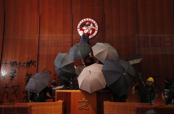 Protesters deface the Hong Kong logo at the Legislative Council to protest against the extradition bill in Hong Kong, Monday, July 1, 2019. The extradition law has aroused concerns that this legislation would undermine the city's independent judicial system as it allows Hong Kong to hand over fugitives to the jurisdictions that the city doesn't currently have an extradition agreement with, including mainland China, where a fair trial might not be guaranteed. (AP Photo/Vincent Yu)