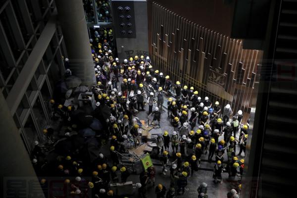 Protesters gather inside the Legislative Council building in Hong Kong, Monday, July 1, 2019. Protesters in Hong Kong took over the legislature's main building Monday night, tearing down portraits of legislative leaders and spray painting pro-democracy slogans on the walls of the main chamber.(AP Photo/Kin Cheung)