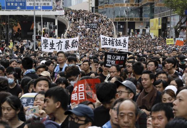 Protesters march banners some of which read "Students did not riot" and "Independent investigation of Police actions" in Hong Kong on Sunday, July 7, 2019. Thousands of people, many wearing black shirts and some carrying British flags, were marching in Hong Kong on Sunday, targeting a mainland Chinese audience as a month-old protest movement showed no signs of abating. (AP Photo/Vincent Yu)
