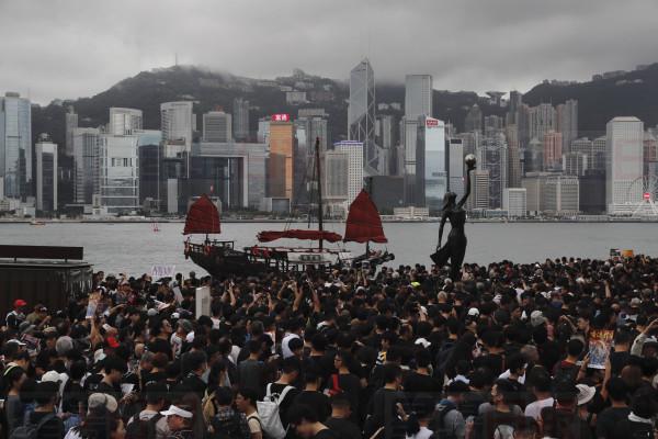 Protesters march near the skyline of Hong Kong on Sunday, July 7, 2019. Thousands of people, many wearing black shirts and some carrying British flags, were marching in Hong Kong on Sunday, targeting a mainland Chinese audience as a month-old protest movement showed no signs of abating. (AP Photo/Kin Cheung)
