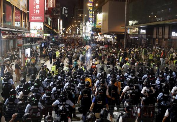 Layers of police officers face-off with protesters in Hong Kong on Sunday, July 7, 2019. Tens of thousands of people, many wearing black shirts and some carrying British colonial-era flags, marched in Hong Kong on Sunday, targeting a mainland Chinese audience as a month-old protest movement showed no signs of abating. (AP Photo/Vincent Yu)