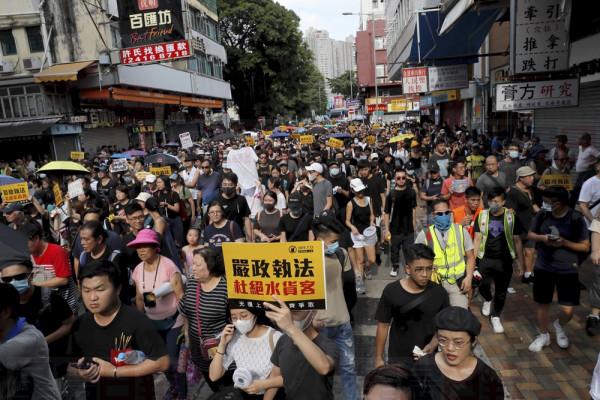 Protesters hold up words that read: "Strict enforcing of law against smugglers of grey goods" in Hong Kong Saturday, July 13, 2019. Several thousand people are marching in Hong Kong against traders from mainland China in what is fast becoming a summer of unrest in the semi-autonomous Chinese territory. (AP Photo/Kin Cheung)