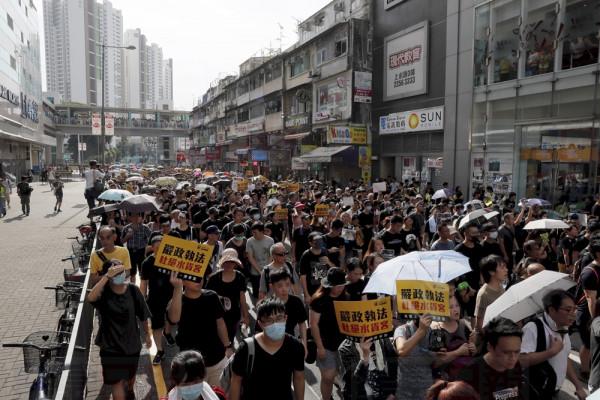 Protesters hold up words that read: "Strict enforcing of law against smugglers of grey goods" as they march in Hong Kong Saturday, July 13, 2019. Several thousand people are marching in Hong Kong against traders from mainland China in what is fast becoming a summer of unrest in the semi-autonomous Chinese territory. (AP Photo/Kin Cheung)