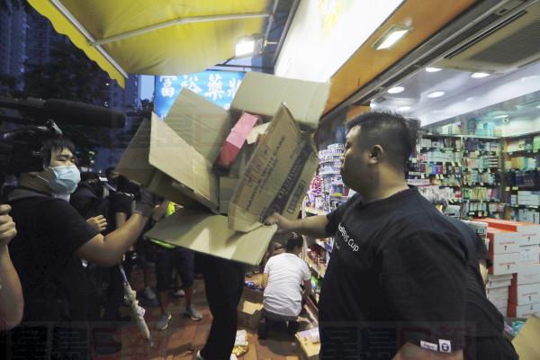 A store worker tries to stop a protester at left from throwing a box of goods at a dispensary that sells to mainland customers, in Hong Kong, Saturday, July 13, 2019. Several thousand people marched in Hong Kong on Saturday against traders from mainland China in what is fast becoming a summer of unrest in the semi-autonomous Chinese territory. (AP Photo/Kin Cheung)