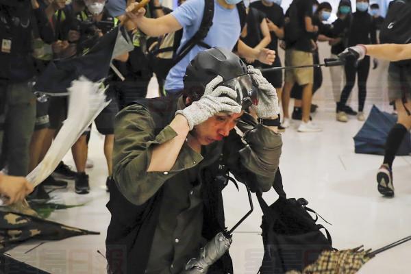 A policeman reacts as he attack by protesters inside a mall in Sha Tin District in Hong Kong, Sunday, July 14, 2019. Police in Hong Kong have fought with protesters as they broke up a demonstration by thousands of people demanding the resignation of the Chinese territory's chief executive and an investigation into complains of police violence. (AP Photo/Kin Cheung)
