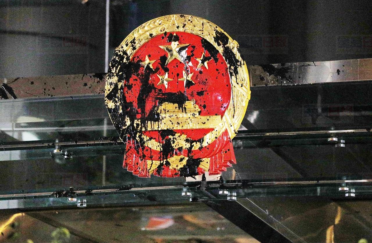 The National Emblem of the People's Republic of China is covered in black paint thrown by protesters outside the Chinese Liaison Office in Hong Kong, Sunday, July 21, 2019. Protesters in Hong Kong pressed on Sunday past the designated end point for a march in which tens of thousands repeated demands for direct elections in the Chinese territory and an independent investigation into police tactics used in previous demonstrations. (AP Photo/Bobby Yip)
