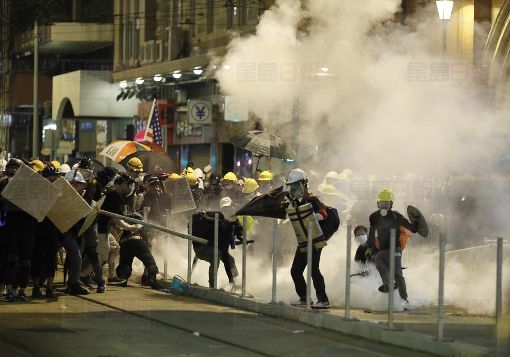 Protesters react to teargas as they confront riot police officers in Hong Kong on Sunday, July 21, 2019. Protesters in Hong Kong pressed on Sunday past the designated end point for a march in which tens of thousands repeated demands for direct elections in the Chinese territory and an independent investigation into police tactics used in previous demonstrations. (AP Photo/Vincent Yu)