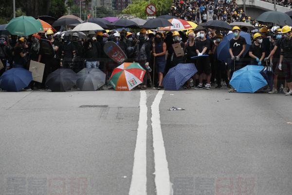 Protesters face off against riot police at the entrance to a village at Yuen Long district in Hong Kong Saturday, July 27, 2019. Protesters wearing black streamed through Yuen Long, even though police refused to grant permission for the march, citing risks of confrontations between demonstrators and local residents. (AP Photo/Bobby Yip)
