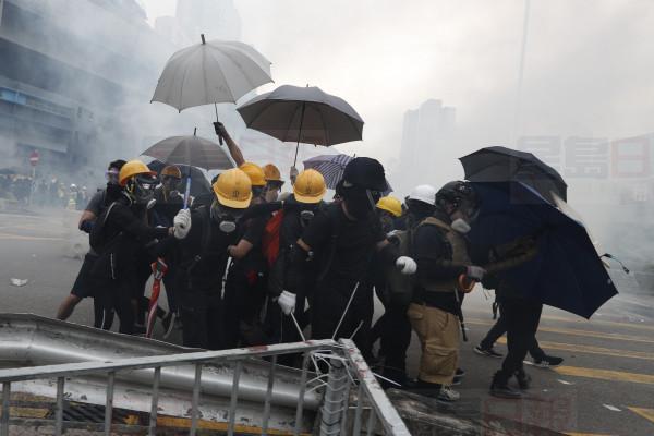 Protesters react to tear gas during a face off with riot police at Yuen Long district in Hong Kong Saturday, July 27, 2019. Police shot tear gas at protesters who defied authorities' warnings not to march in a neighborhood where six days earlier a mob apparently targeting demonstrators brutally attacked people in a commuter rail station. (AP Photo/Bobby Yip)
