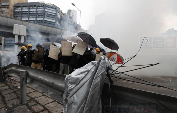 Protesters react to tear gas during a face off with riot police at Yuen Long district in Hong Kong Saturday, July 27, 2019. Police in Hong Kong shot tear gas at protesters who defied authorities' warnings not to march in a neighborhood where six days earlier a mob apparently targeting demonstrators brutally attacked people in a commuter rail station. (AP Photo/Bobby Yip)
