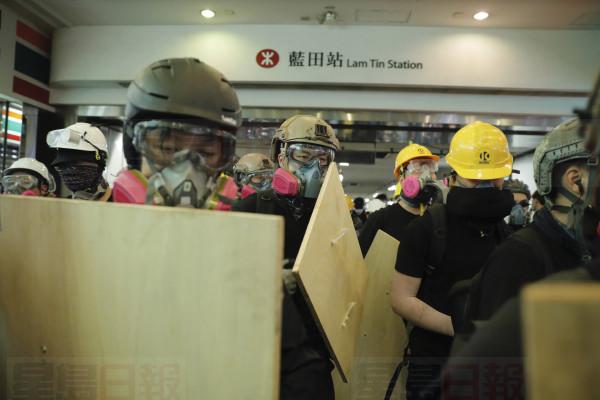 Protesters with makeshift shields pass through a subway station on their way to a police station in Hong Kong on Sunday, Aug. 4, 2019. Demonstrators in Hong Kong moved en masse to a luxury shopping district Sunday evening after riot police used tear gas to clear out an area they were previously occupying, as the 2-month-old protest movement showed no signs of easing. (AP Photo/Kin Cheung)