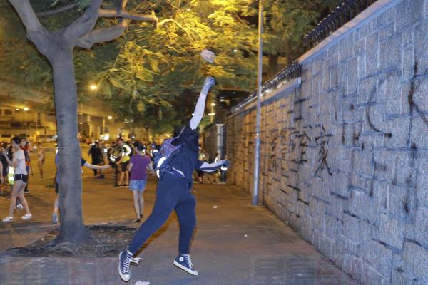 A protester throws a brick into a police station compound in Hong Kong on Sunday, Aug. 4, 2019. Demonstrators in Hong Kong moved en masse to a luxury shopping district Sunday evening after riot police used tear gas to clear out an area they were previously occupying, as the 2-month-old protest movement showed no signs of easing. (AP Photo/Kin Cheung)