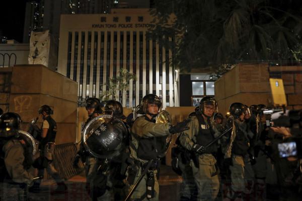 Riot policemen retreat after protesters and residents gather outside the Kwun tong police station in Hong Kong, Sunday, Aug. 4, 2019. The first of two planned protests in Hong Kong on Sunday has kicked off from a public park just hours after police said they arrested more than 20 people for unlawful assembly and other offences during the previous night's demonstrations. (AP Photo/Vincent Thian)